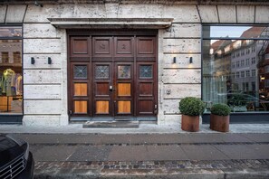 Une grande porte à deux battants en bois, avec des panneaux de verre, et une petite plante en pot placée à côté.