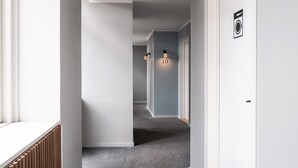 A hallway with grey carpet, white walls, and a door with a laundry symbol.