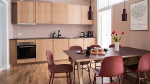 A modern kitchen with wooden cabinets, a black oven, and a dining area with a table and chairs.