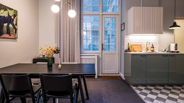 A modern kitchen with a dining area, featuring a large window, pendant lights, and a checkered floor. - The Citadel 2 by Daniel&Jacob's (København)