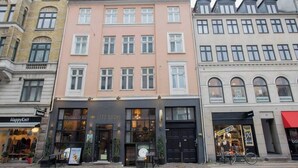 Een gebouw met een restaurant genaamd 'Letz Sushi' op de begane grond en een winkel genaamd 'HappyKnit' op de tweede verdieping.