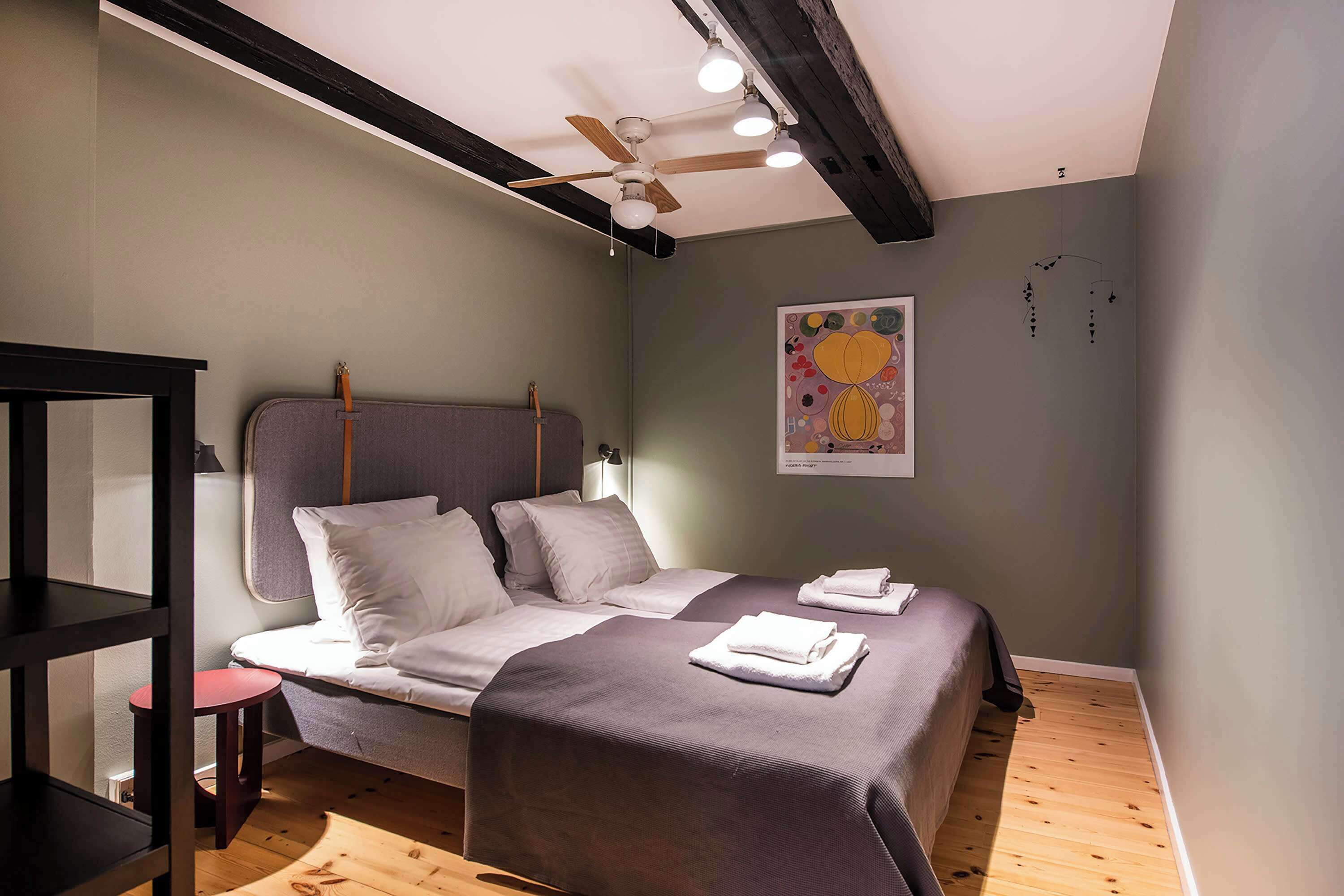 A bedroom with a bed, a small table, and a ceiling fan.