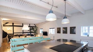 Een moderne keuken met een groot eiland, hanglampen en een gezellig zithoek met een bank en stoelen.