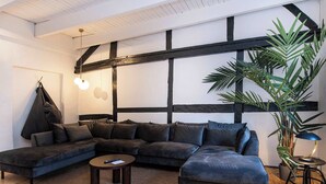 Een moderne woonkamer met een hoekbank, een ronde salontafel en een hanglamp.