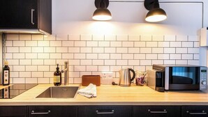 Een moderne keuken met een houten aanrecht, een roestvrijstalen spoelbak, een waterkoker, een magnetron en twee hanglampen.