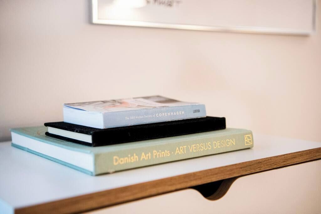 A stack of books on a white shelf.