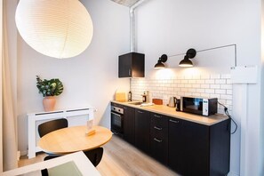 Modern kitchen with a round dining table, microwave, and kettle, perfect for cooking and dining.