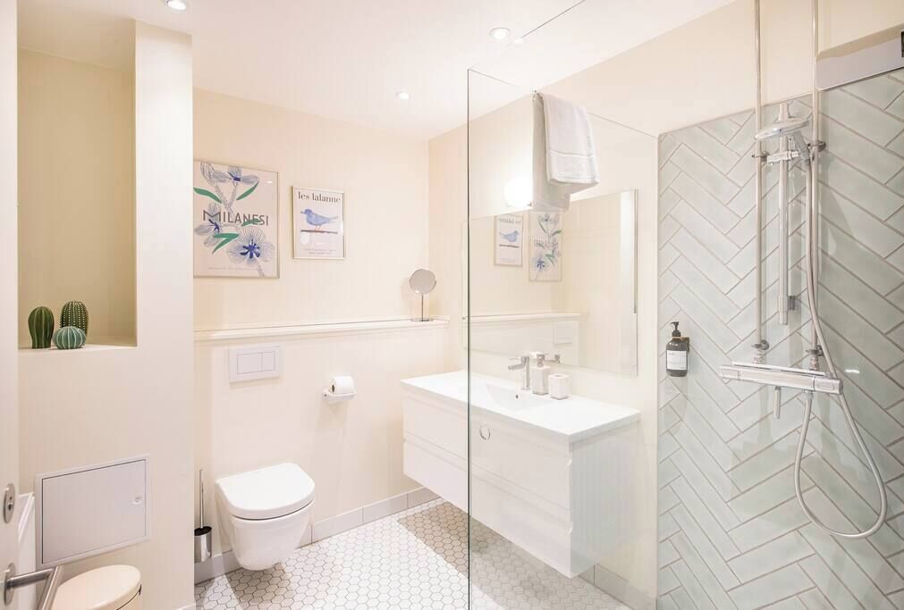 Un baño moderno con cabina de ducha de vidrio, inodoro blanco y tocador con espejo.