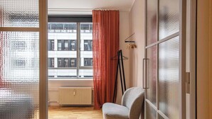 Une pièce moderne dotée d’une grande fenêtre, d’un radiateur, d’une chaise et d’un porte-manteau.