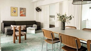 A modern living room with a sofa, a dining table, chairs, a coffee table, and a large mirror.