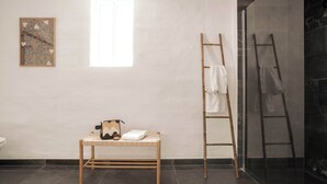 A bathroom with a wooden bench, a ladder, and a shower area.