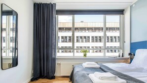 A hotel room with a large window, a bed with neatly folded towels, a mirror, and a radiator. - The Lakes 1BR swanky by Daniel & Jacob's (København)