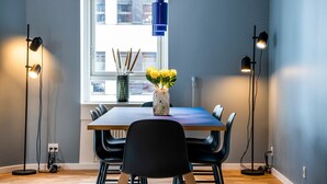 A dining area with a table, chairs, a vase with flowers, and pendant lights.
