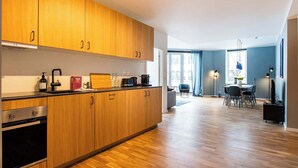 A modern kitchen with wooden cabinets, a built-in oven, and a dining area with a table and chairs.