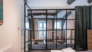Ein Zimmer mit einem Bett, einem Fenster und Blick auf eine Treppe.