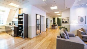 En moderne lejlighed med køkken, spiseområde og opholdsstue, med loft til kip og store vinduer.