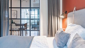 Et hotelværelse med seng, skrivebord og udsigt ud.