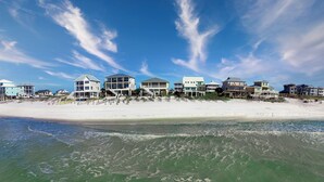 A beachfront property with multiple houses, a sandy beach, and ocean waves.