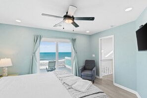A bedroom with a bed, a chair, a ceiling fan, and a view of the ocean through a sliding door. - 4 bdrm, Beach Front, Sun-Sun Pet Friendly (Cape San Blas)