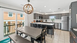 A modern kitchen with a central island, stainless steel appliances, and a dining area with a bench and chairs.