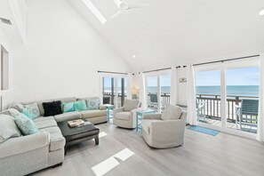 A spacious living room with a high ceiling, a large window overlooking the beach, and a balcony with a view of the ocean. - 4 bdrm, Beach Front, Sun-Sun Pet Friendly (Cape San Blas)