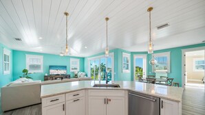 A spacious kitchen with a large island, white cabinetry, and pendant lighting. - Bluetique:  Monthly luxury beach home, private pool, rooftop deck (Holmes Beach)
