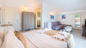 Een moderne hotelkamer met een groot bed, een bank, een bureau en een kledingkast.