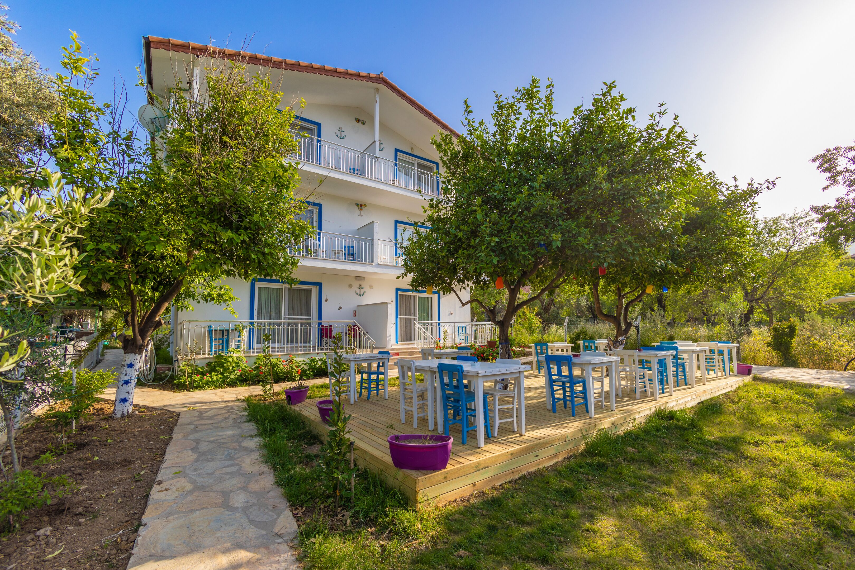 A multi-story building with balconies, outdoor seating, and a garden area.