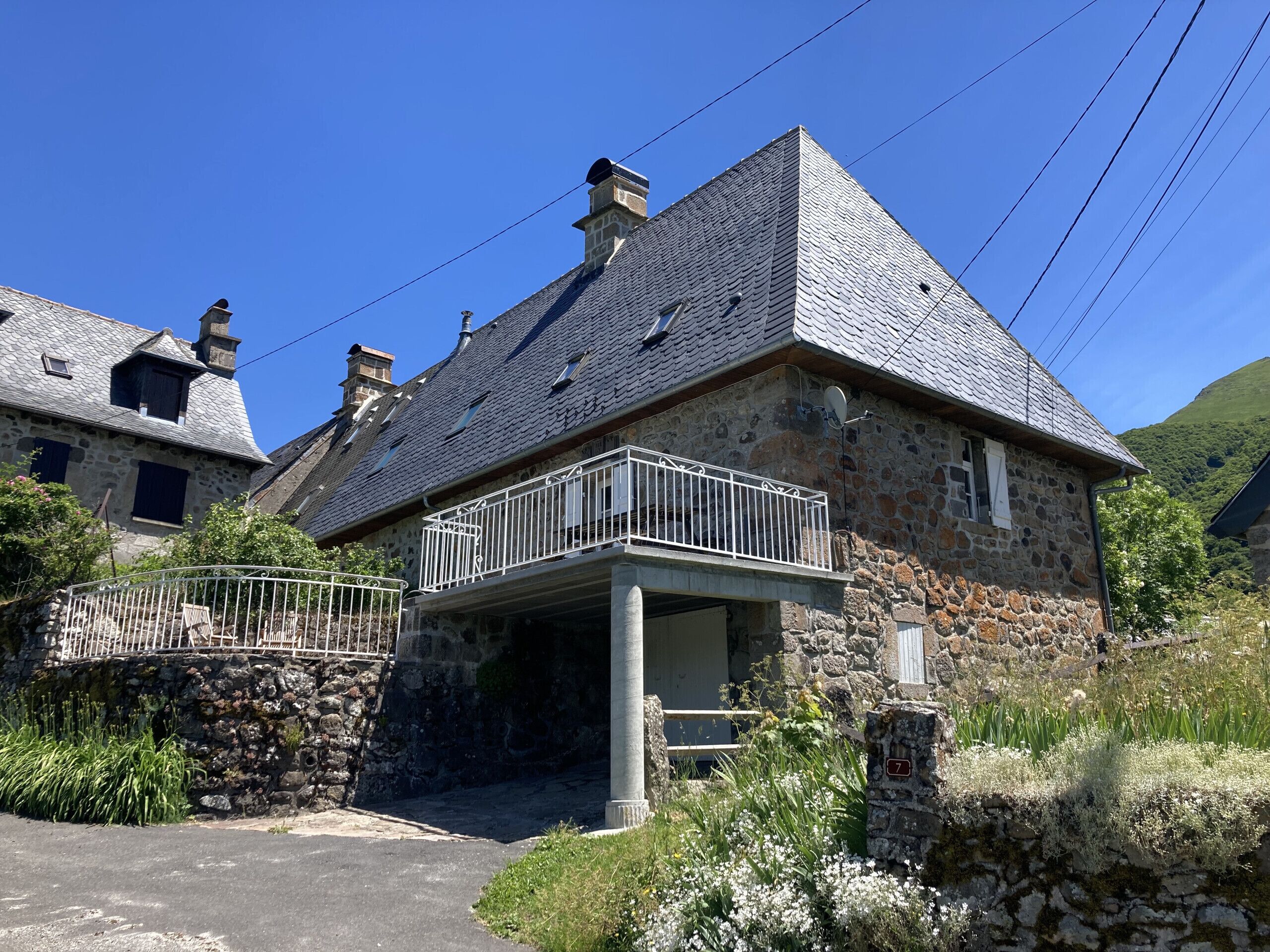 Un bâtiment en pierre doté d’un balcon, d’un mur en pierre et d’un panneau indiquant un numéro.