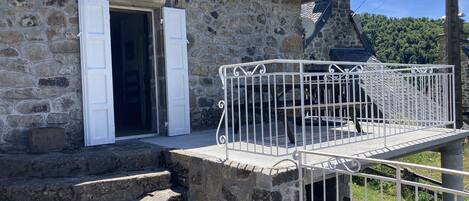 Un edificio de piedra con un balcón de metal y escaleras que conducen a una puerta.