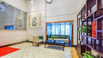 A hotel lobby with a reception desk, seating area, and decorative elements.