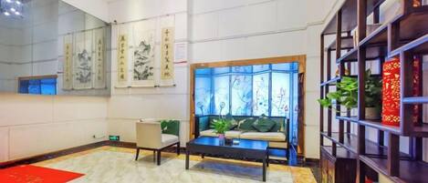 A hotel lobby with a reception desk, seating area, and decorative elements.