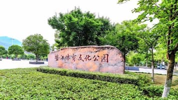 A stone sign with Chinese characters, surrounded by well-maintained hedges and trees.