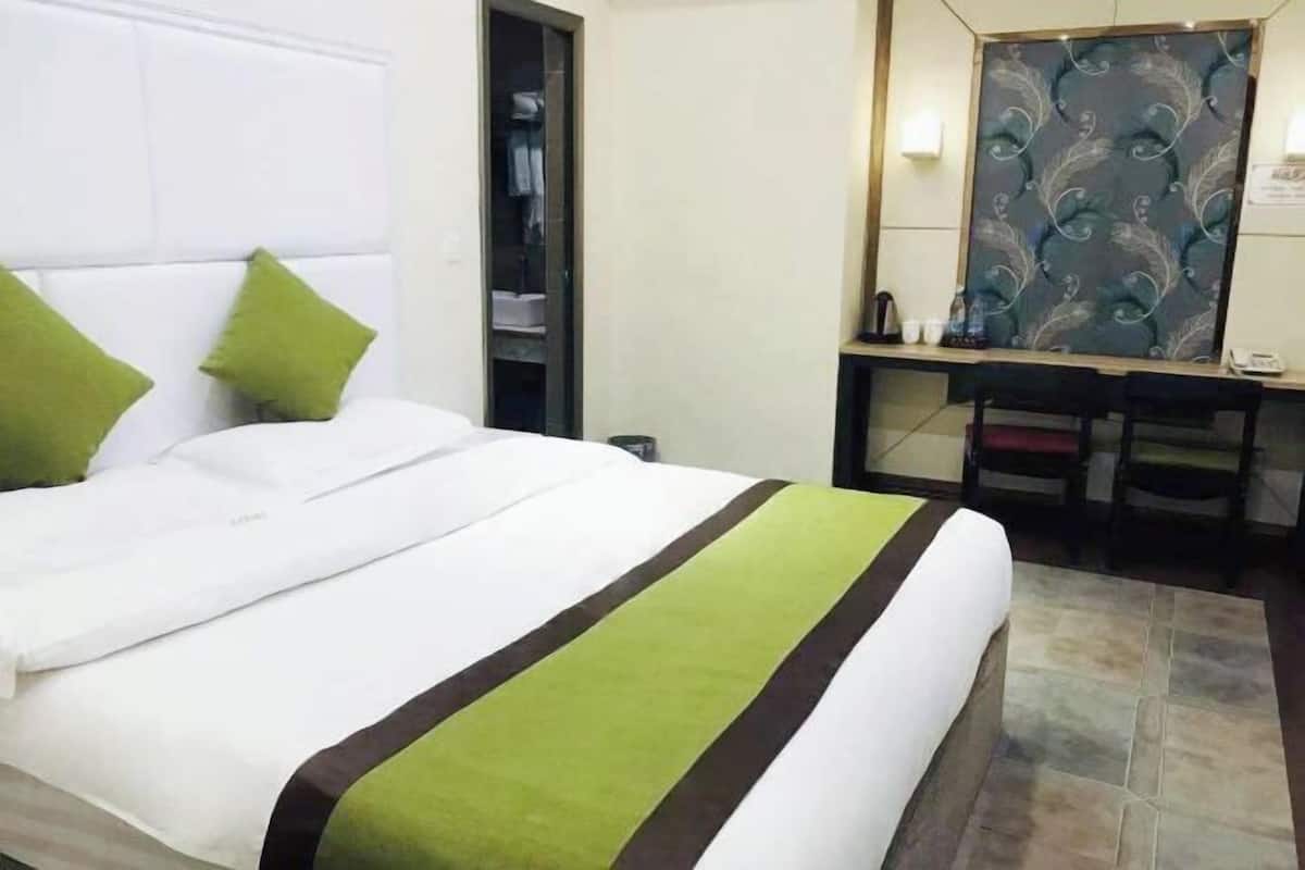 A hotel room with a bed, a desk, a mirror, and a wardrobe.