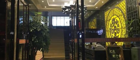 A hotel entrance with a glass door, a staircase, and a wall with a decorative pattern.