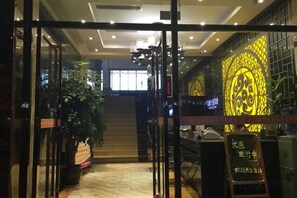 A hotel entrance with a glass door, a staircase, and a wall with a decorative pattern. - Nanhao Business Hotel (Dianjiang County)
