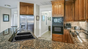 A kitchen with granite countertops, stainless steel appliances, wooden cabinets, and a built-in oven. - Golf Cart ~ Golf Course View ~ Community Pool (Miramar Beach)