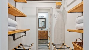 Un cuarto de lavandería con estantes de madera, tendederos y un espejo.