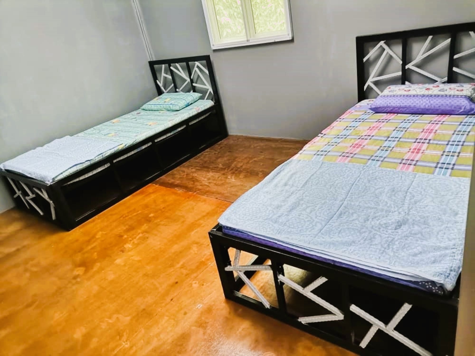 Quarto com duas camas de solteiro, soalho de madeira e janela com vista.