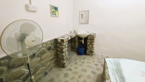 A bathroom with a fan, sink, and stone wall. - Hotel O Flinstone Lodge (Kota Belud)
