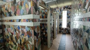 A corridor with mosaic walls and a tiled floor, leading to a bright room with a window. - Hotel O Flinstone Lodge (Kota Belud)