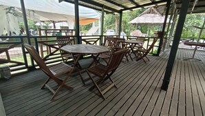 An outdoor wooden deck with a round table and chairs, surrounded by a metal railing. - Hotel O Flinstone Lodge (Kota Belud)