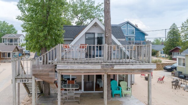Une terrasse en bois avec des sièges extérieurs et un escalier menant à un deuxième étage.