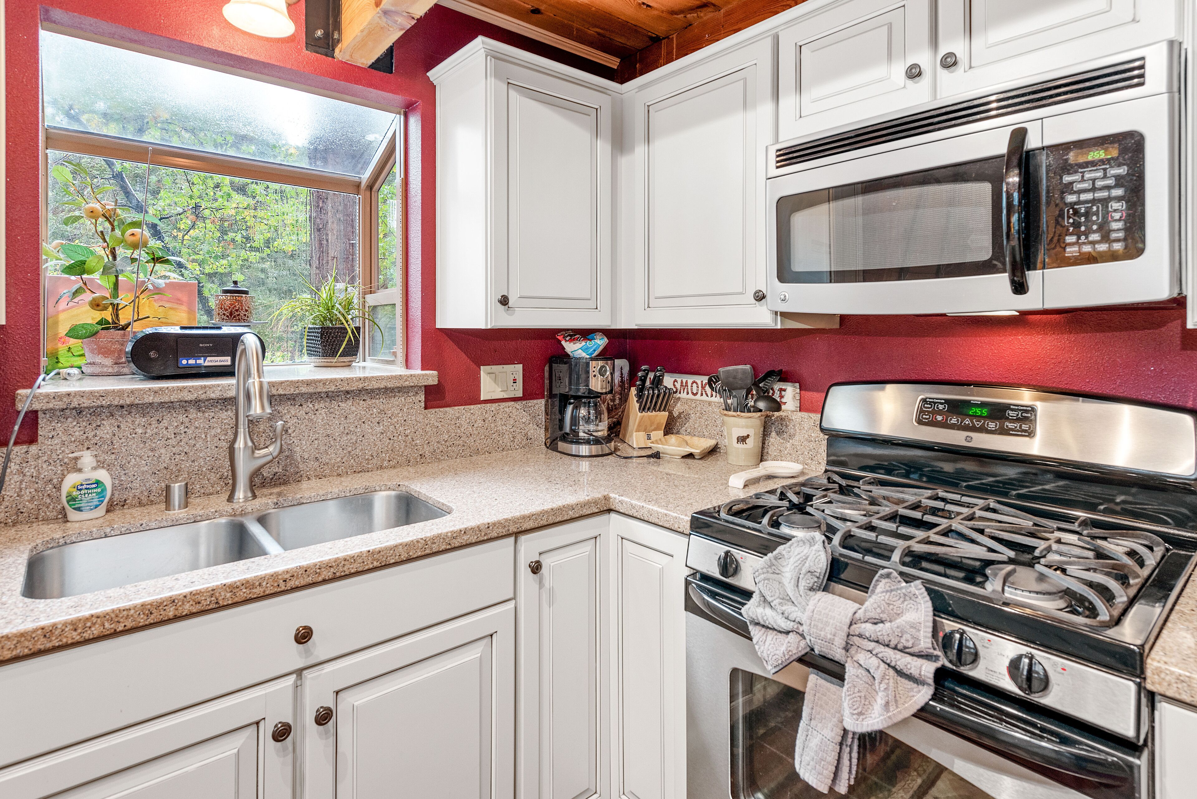 A kitchen with white cabinets, a stainless steel stove, a microwave, and a sink.