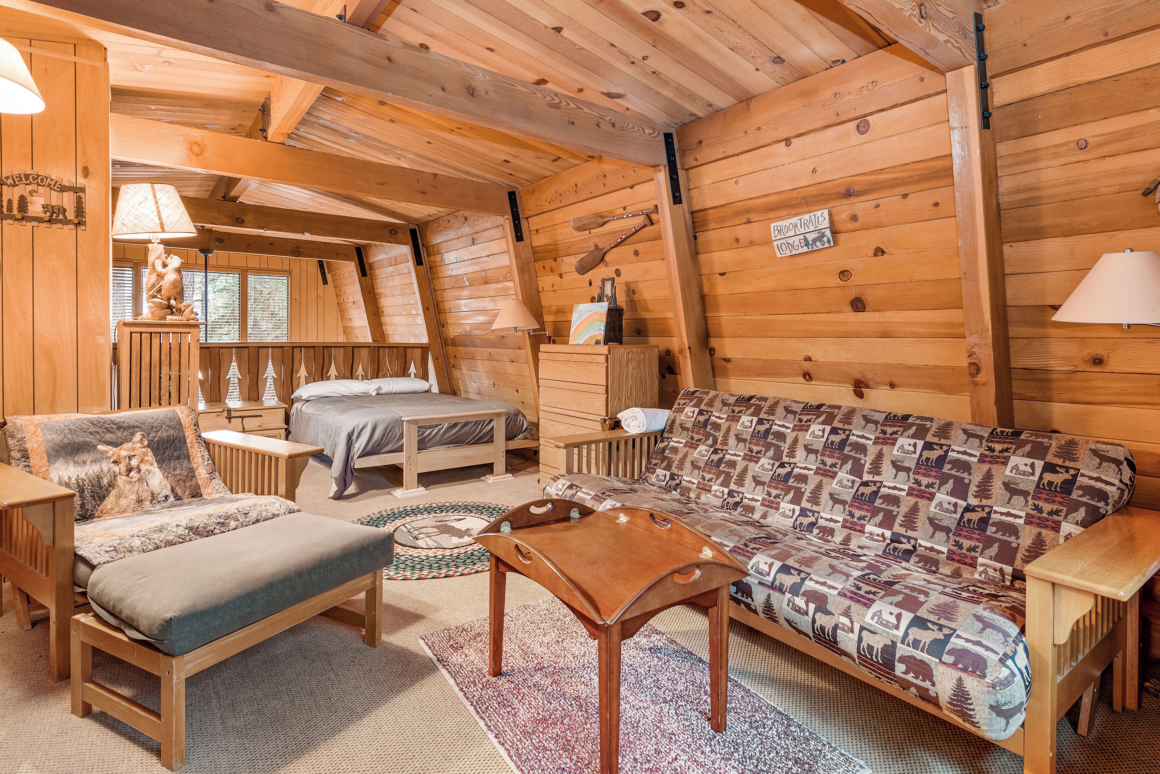 Un interior acogedor de cabaña con cama, sofá y muebles de madera.