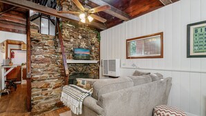 A cozy living room with a stone fireplace, a ceiling fan, and a calendar on the wall.