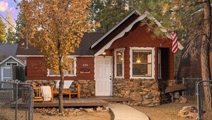A rustic cabin with a stone exterior, a wooden deck, and a mailbox.