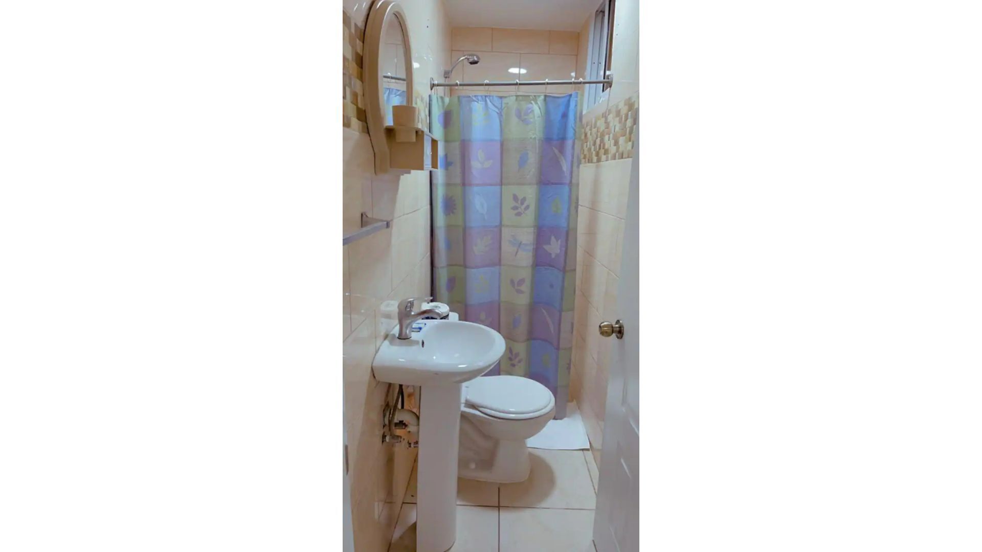 Un baño pequeño con lavamanos, inodoro y cortina de ducha blancos.