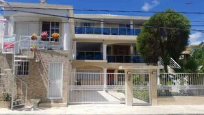 A two-story building with a gated entrance, a balcony on the upper floor, and a staircase leading to the entrance. - Fully Equipped New 3BR APT->DT->2Mins to the Beach (Sosúa)