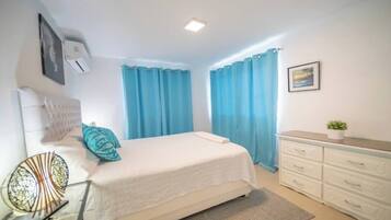 Un dormitorio con cama, cómoda, espejo y cortinas.